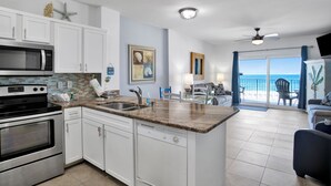A modern kitchen with white cabinets, a granite countertop, and a view to the outside.
