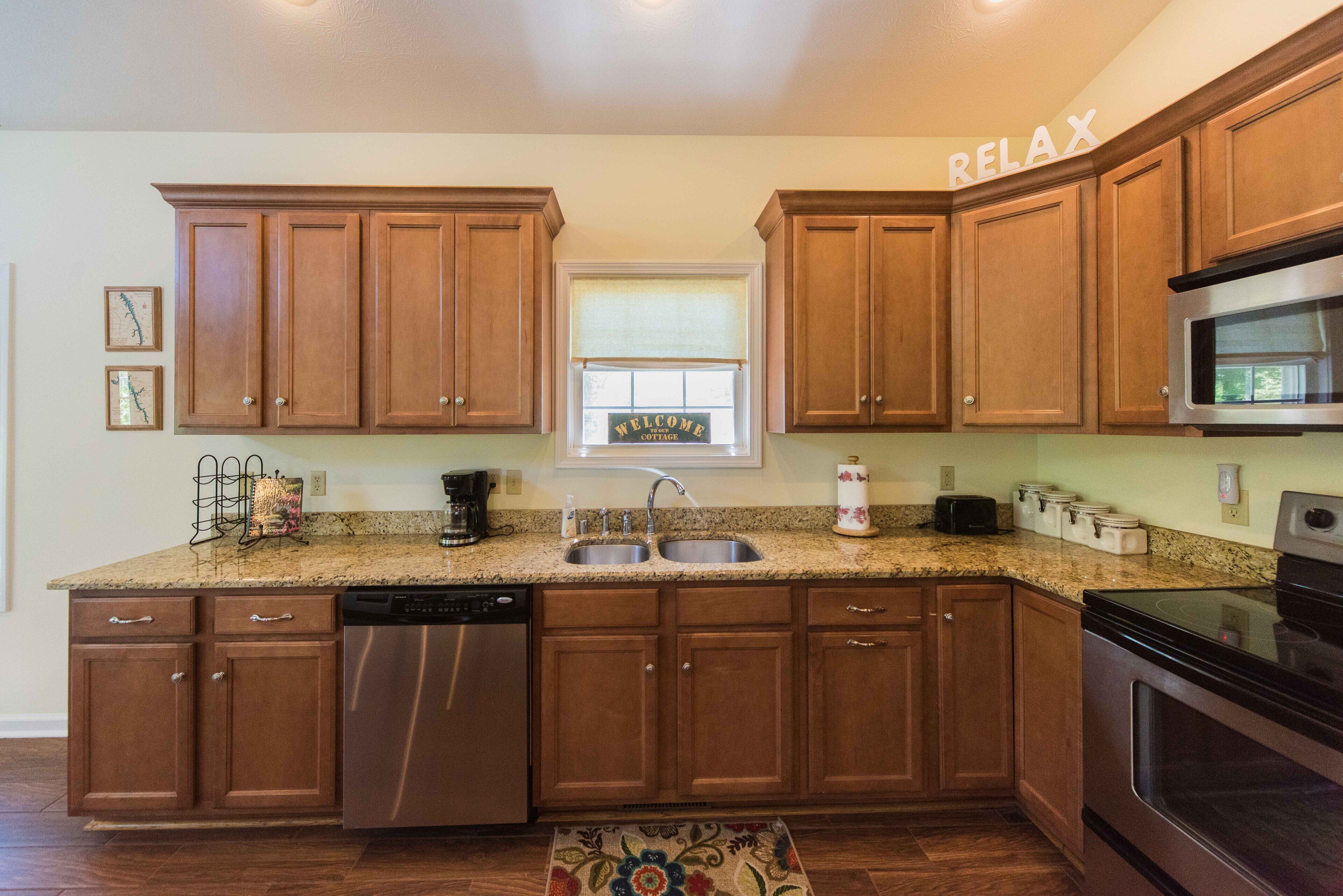 A kitchen with wooden cabinets, a stainless steel refrigerator, a dishwasher, a double sink, and a microwave.