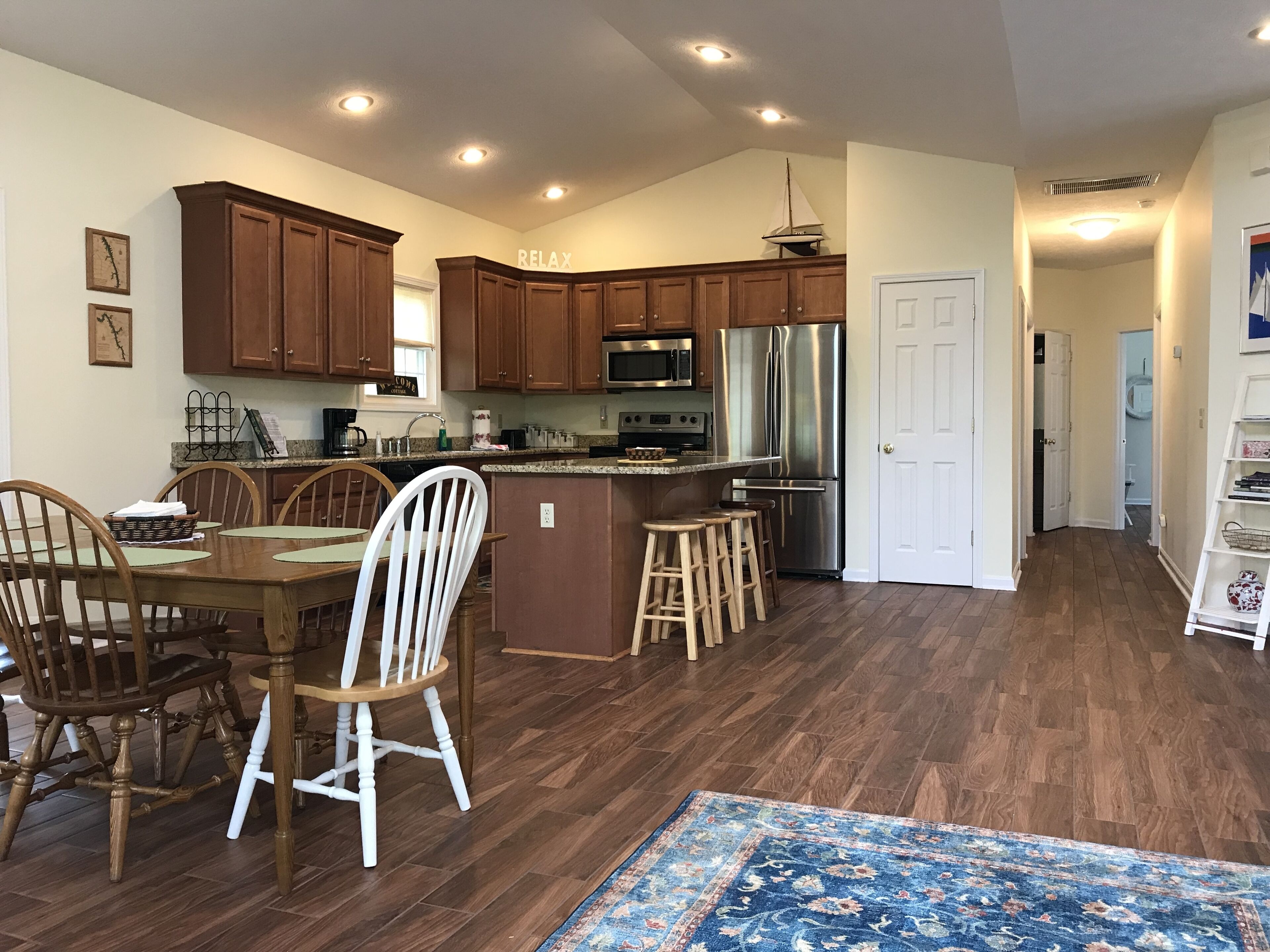 A spacious kitchen with wooden cabinets, a stainless steel refrigerator, and a dining area with wooden chairs and a table.