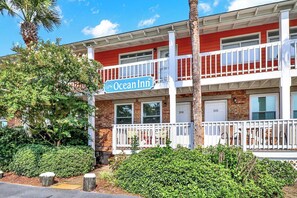 A two-story building with a red facade, white railings, and a sign reading "Ocean Inn." - Isle Of Palms Condo, half block to beach, enter with combo, private entrance. (Isle of Palms)