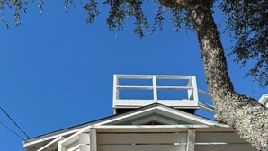 Un bâtiment à deux étages doté d’un balcon, d’un numéro de maison bien visible et d’un arbre au premier plan.
