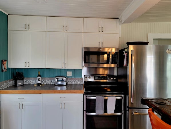 Modern kitchen with white cabinetry, stainless steel appliances, and a mosaic tile backsplash.
