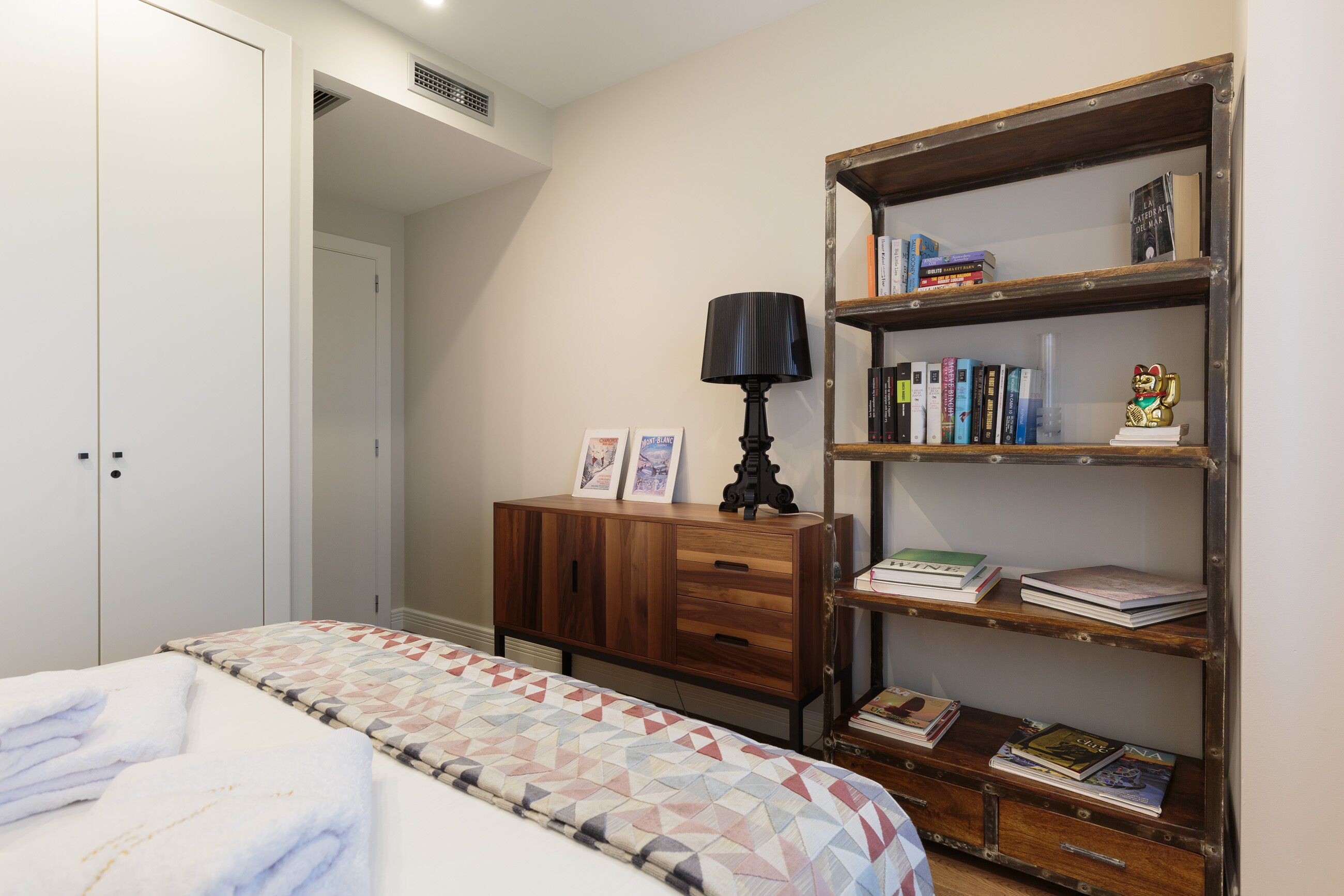 A bedroom with a bed, a wooden dresser, and a bookshelf.