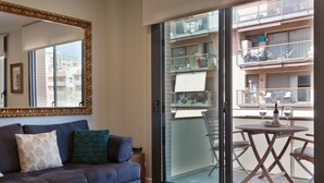 A modern living room with a sofa, a coffee table, and a sliding glass door leading to a balcony.