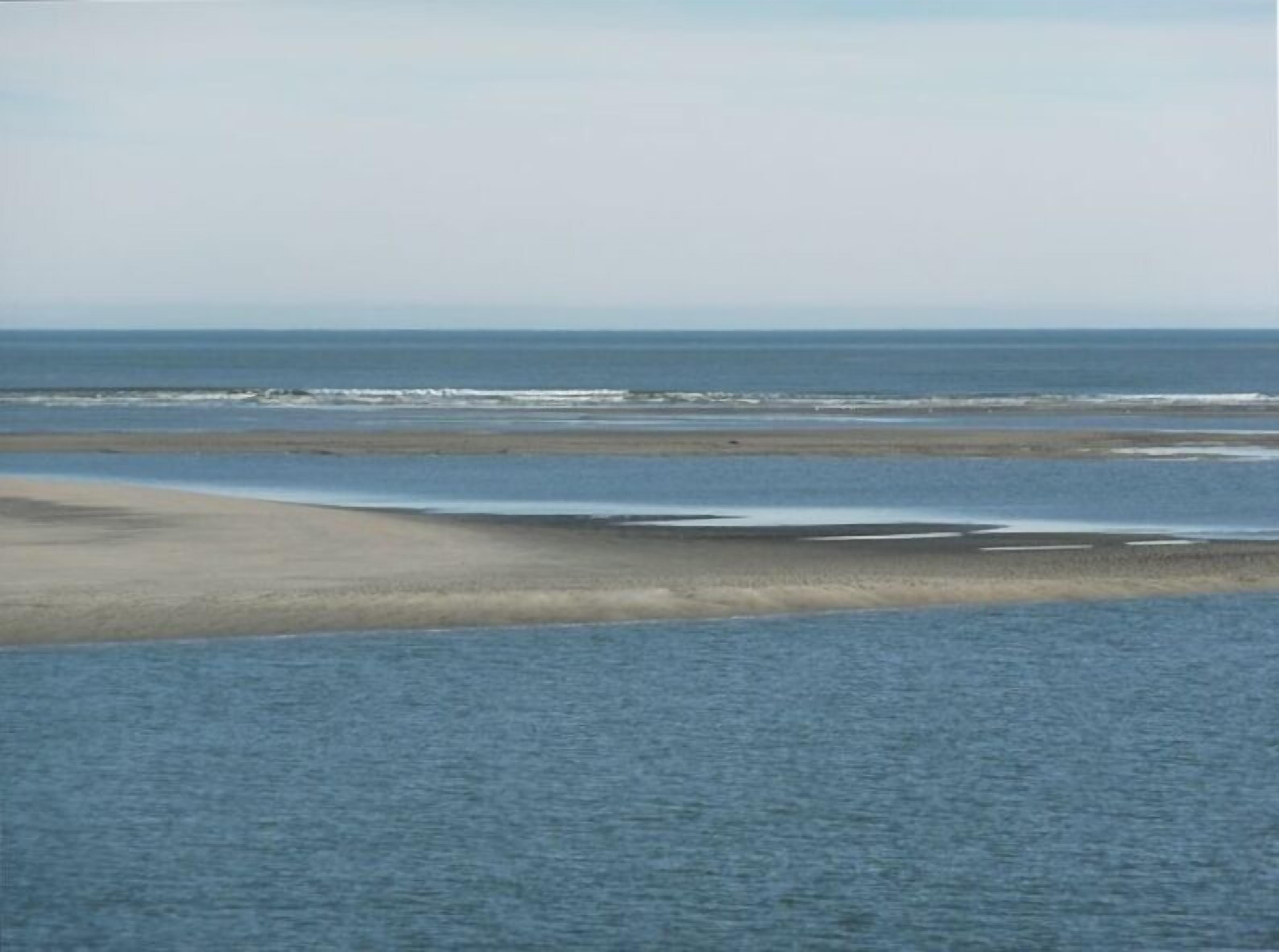 A beach with a wide sandy area and calm water.