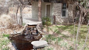 A rustic stone house with a small pond and a stone bridge.