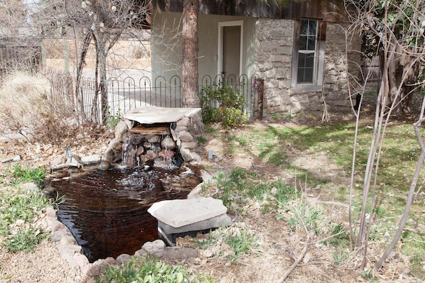 A rustic stone house with a small pond and a stone bridge.