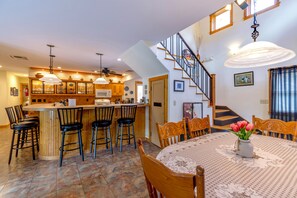 A spacious kitchen with a central island, wooden chairs, and a dining table with a vase of flowers. - Large 4 bed, 2 bath luxury home, views, patios for up to 8 guests (Bisbee)