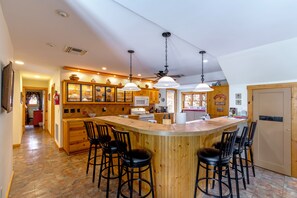 A spacious kitchen with a central island, wooden cabinetry, and bar stools. - Large 4 bed, 2 bath luxury home, views, patios for up to 8 guests (Bisbee)