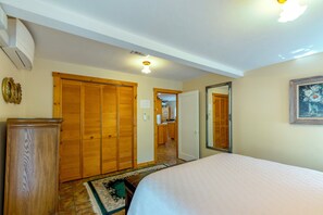 A bedroom with a bed, wooden wardrobe, and a mirror on the wall.