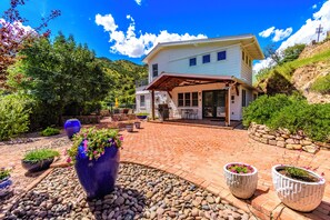 A two-story house with a covered patio, surrounded by a landscaped garden with potted plants and a stone wall. - Large 4 bed, 2 bath luxury home, views, patios for up to 8 guests (Bisbee)
