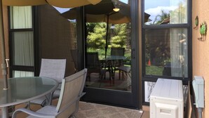 Un patio con puerta de vidrio, una mesa, sillas y una sombrilla.