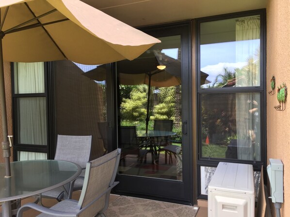 Un patio con puerta de vidrio, una mesa, sillas y una sombrilla.