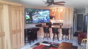 Un espacio habitable compacto con barra, televisor montado en la pared y ventilador de techo.