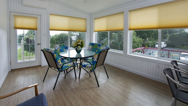 Ein Wintergarten mit rundem Tisch, Stühlen und Deckenventilator.