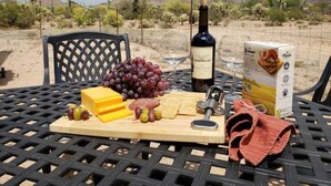 A table set with cheese, grapes, crackers, a bottle of wine, and a box of crackers in a desert landscape. - Endless Tucson Desert Views 3Br2Ba Home 2 Acres Garage Arcade Games Nature Oasis (Tucson)