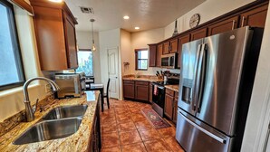 A modern kitchen with stainless steel appliances, granite countertops, and a large refrigerator. - Endless Tucson Desert Views 3Br2Ba Home 2 Acres Garage Arcade Games Nature Oasis (Tucson)