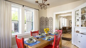 A dining area with a wooden table, red chairs, and a decorative metal partition.