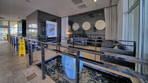 Un hall d’entrée moderne avec un espace salon, un grand vase bleu et un panneau d’avertissement au sol.