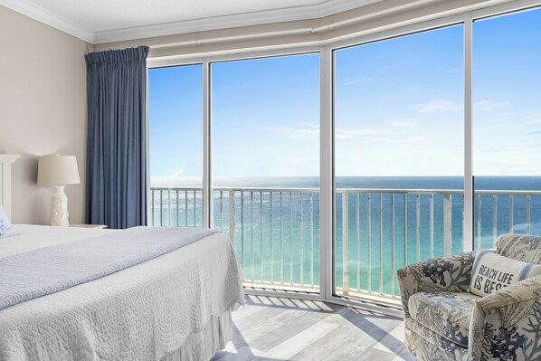 Une chambre d’hôtel avec un grand lit, une chaise et un balcon donnant sur l’océan.