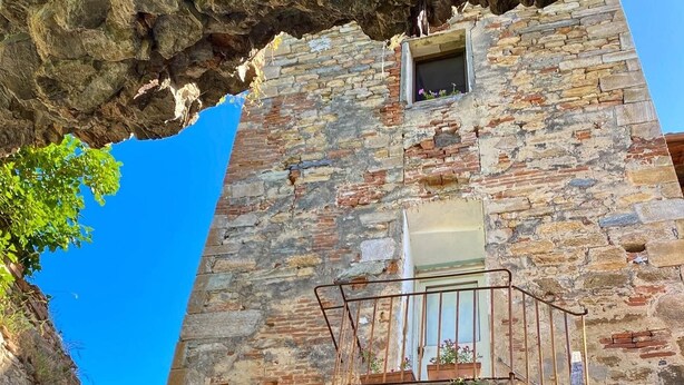 A stone building with a balcony and a small window.
