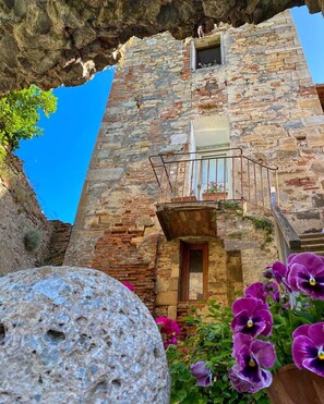 Un edificio de piedra con un balcón y una ventana pequeña.