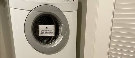 Een gestapelde wasmachine en droger met bedieningsknoppen en een label.