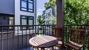 Un balcon avec une table ronde en bois et deux chaises en bois.