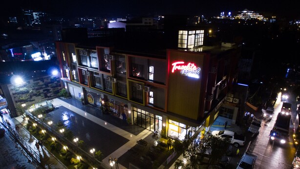 A multi-story hotel with a prominent 'Tranquility Express' sign, featuring a rooftop garden and a spacious outdoor area with a checkered pattern. - Travelite Express Hotel (Baguio)