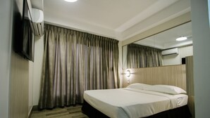 A hotel room with a bed, a television mounted on the wall, and an air conditioning unit. - Travelite Express Hotel (Baguio)
