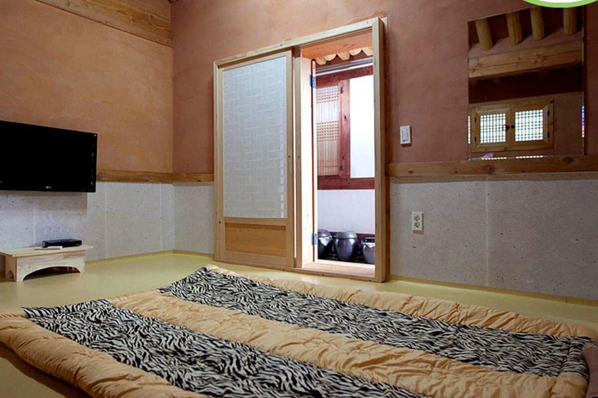 A room with a bed, a television, a sliding door, and a small table.