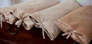 A wooden dresser with rolled-up beige fabric items, possibly linens or towels, tied at the ends.