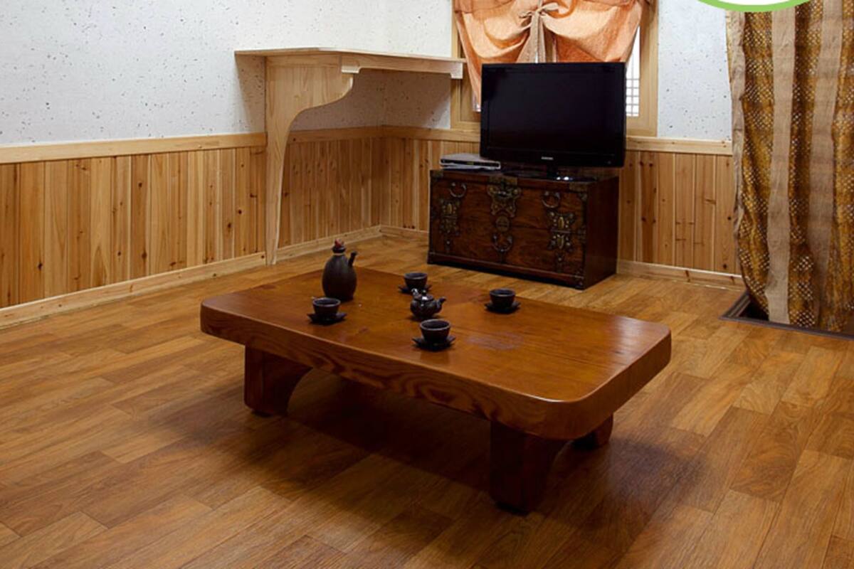 A wooden-paneled room with a wooden table, a television, and a cabinet.