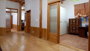 A hallway with wooden flooring, a brown leather sofa, and a wooden cabinet with decorative items. - Songhak Pension (Gyeongju)