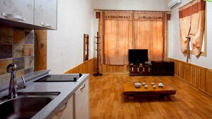 A compact living space with a kitchen area, a dining table with tea sets, and a television. - Songhak Pension (Gyeongju)