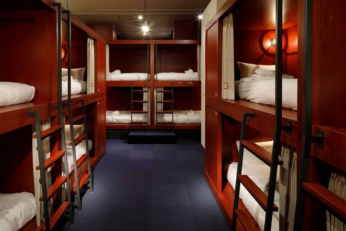 A narrow corridor with bunk beds, wooden walls, and a blue carpet.
