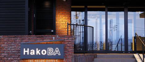 A hotel entrance with a sign reading "HakoBA The Share Hotels".