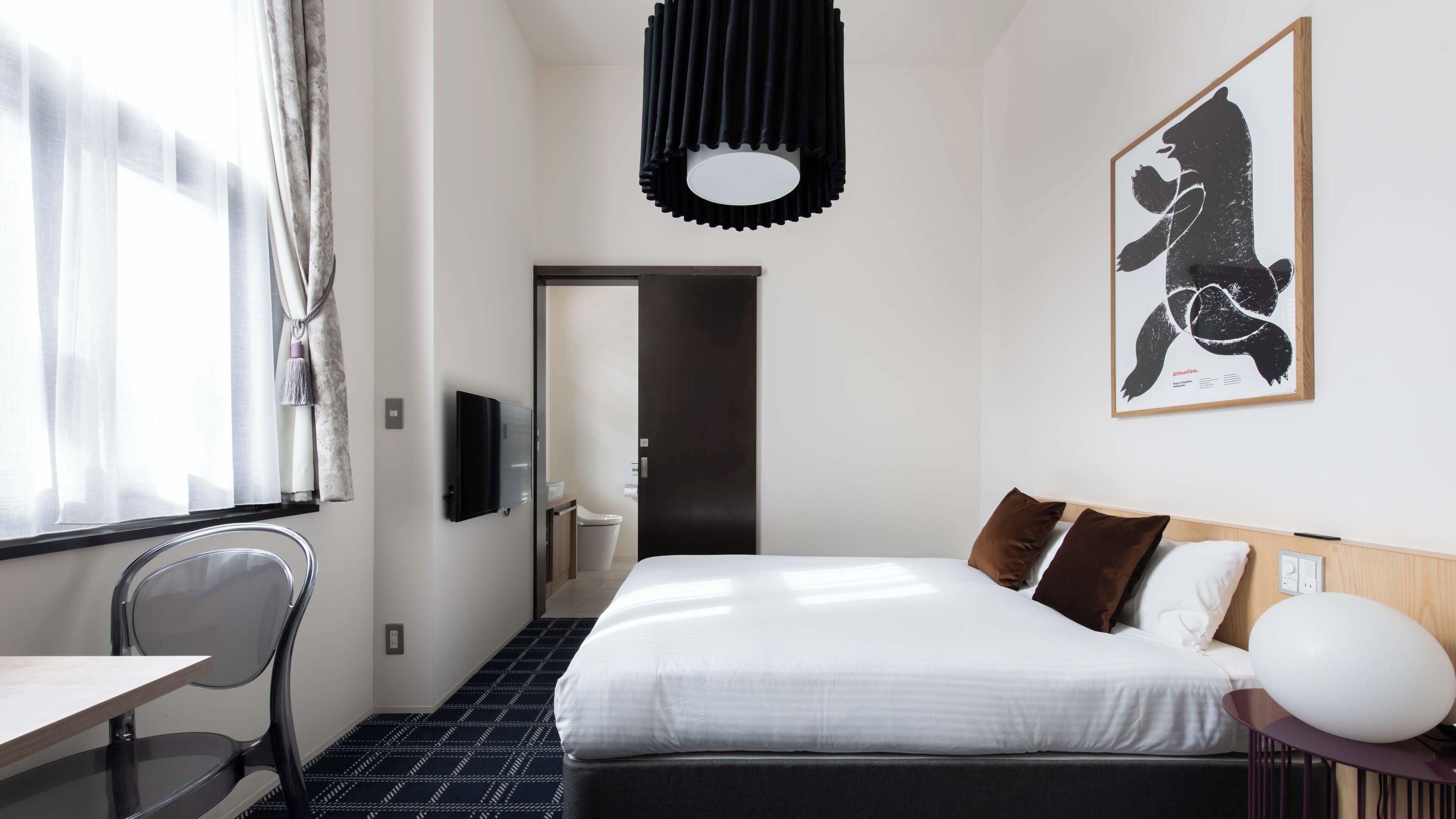 Une chambre d’hôtel comprenant un lit, un bureau, une chaise, une télévision et une œuvre d’art encadrée accrochée au mur.