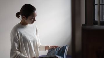 A person sitting on a bed in a room with a window and a door.