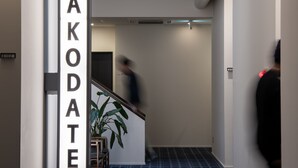 En hall med en skylt som visar texten ”NYA HAKODA” och en mönstrad matta.