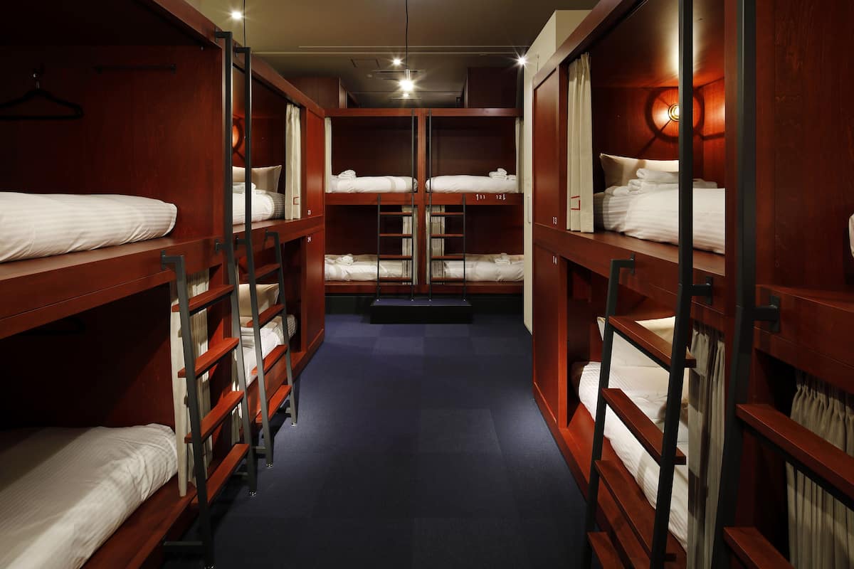 A room with bunk beds, wooden walls, and a carpeted floor.