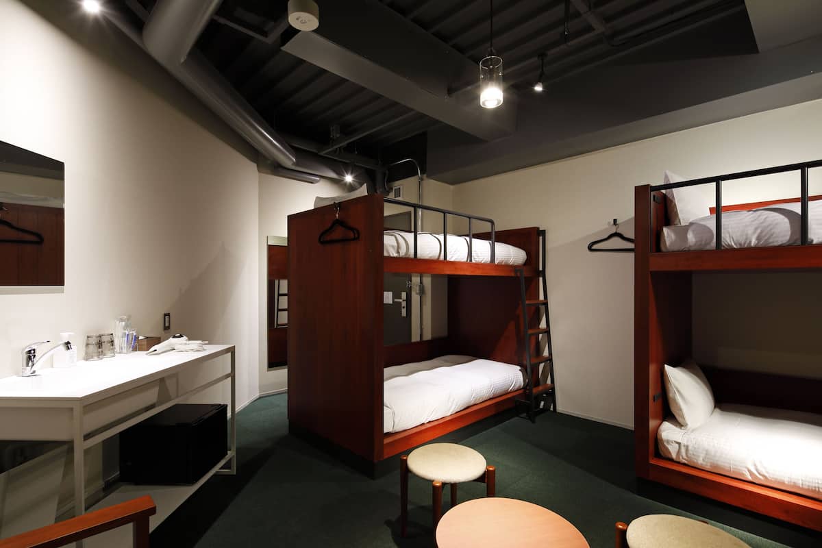 A dormitory room with bunk beds, a desk, and a chair.