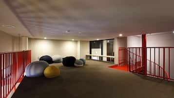 Un intérieur moderne avec un sol recouvert de moquette, des rampes rouges et plusieurs grands fauteuils-pouf colorés.