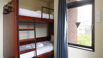 A bunk bed room with a window and curtains.
