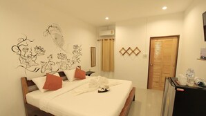 Una cama bien hecha con sábanas blancas y varios almohadones, un aire acondicionado de pared y una puerta de madera.
