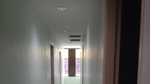 A narrow, well-lit hallway with tiled flooring and a window at the end. - Miri Budget Inn (Miri)