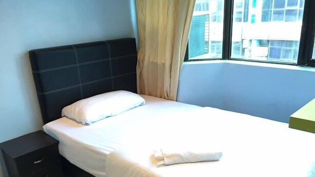 A neatly made bed with white linens in a room with a dark headboard and a window with curtains. - Miri Budget Inn (Miri)