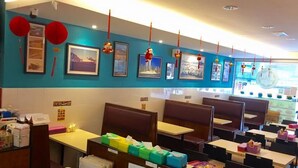 A restaurant with booths and tables, red lanterns, and framed pictures on the wall. - Miri Budget Inn (Miri)