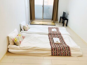A hotel room with two beds, a small table, a TV, and a view of the outside. - At RLiS House Tennoji East (Osaka)
