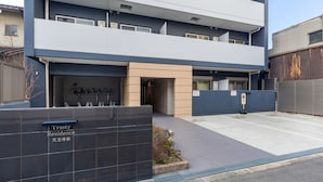 A modern multi-story building with a sign reading "Trusty Residence" and a gated entrance.